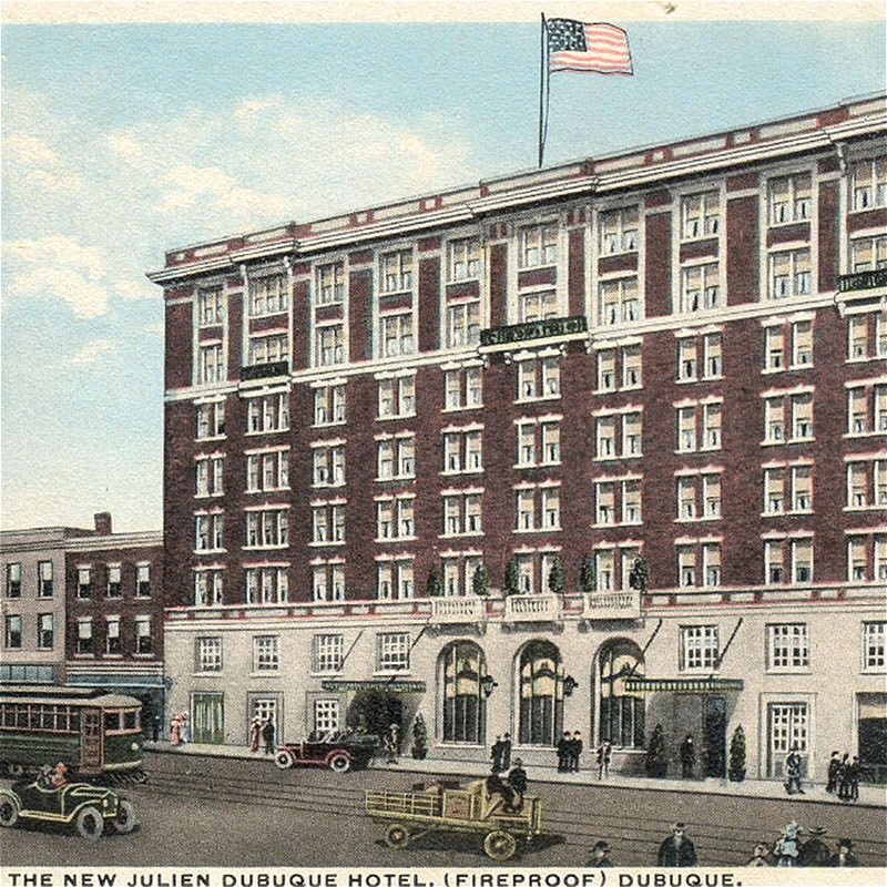 Historic hotel exterior with American flag and vintage vehicles